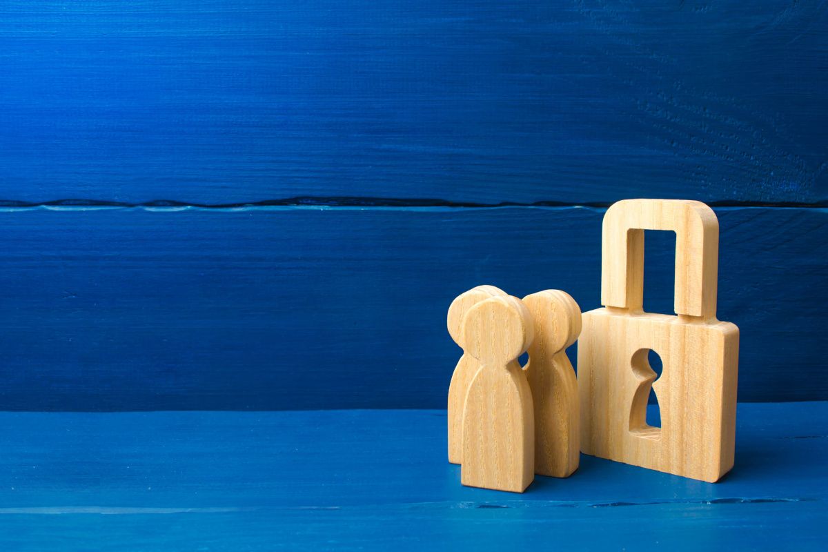 I nostri valori: Riservatezza. L'immagine rappresenta un lucchetto e degli omini di legno, simboleggiando la riservatezza tra persone e non solo relativamente al trattamento informatico dei dati